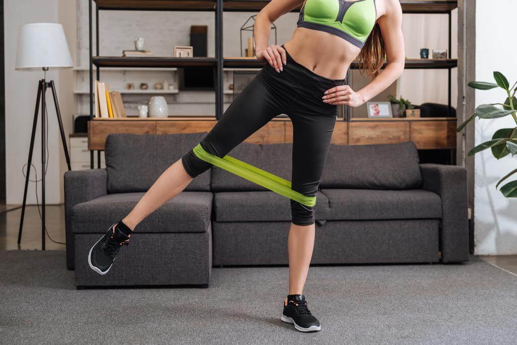 Woman performing exercise with resistance band at home gym setup