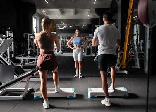 Group workout session with gym equipment and step platforms in a modern fitness center.