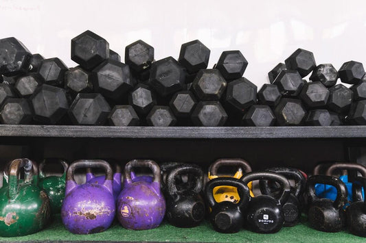 Dumbbells and colorful kettlebells on gym rack showcasing essential gym equipment for varied workouts.