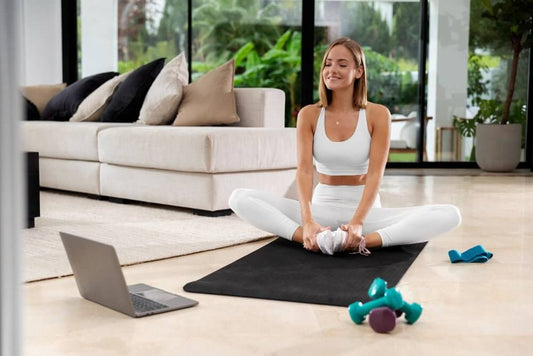 Woman practicing yoga in home gym with dumbbells and laptop, showcasing versatile gym equipment for functional workouts.