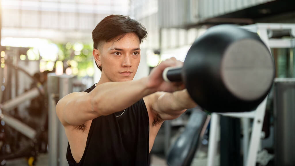 determined strong asian man sportswear working out kettlebell