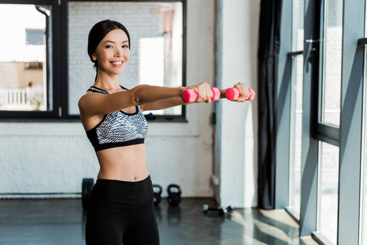 happy girl holding pink dumbbells while exercising gym